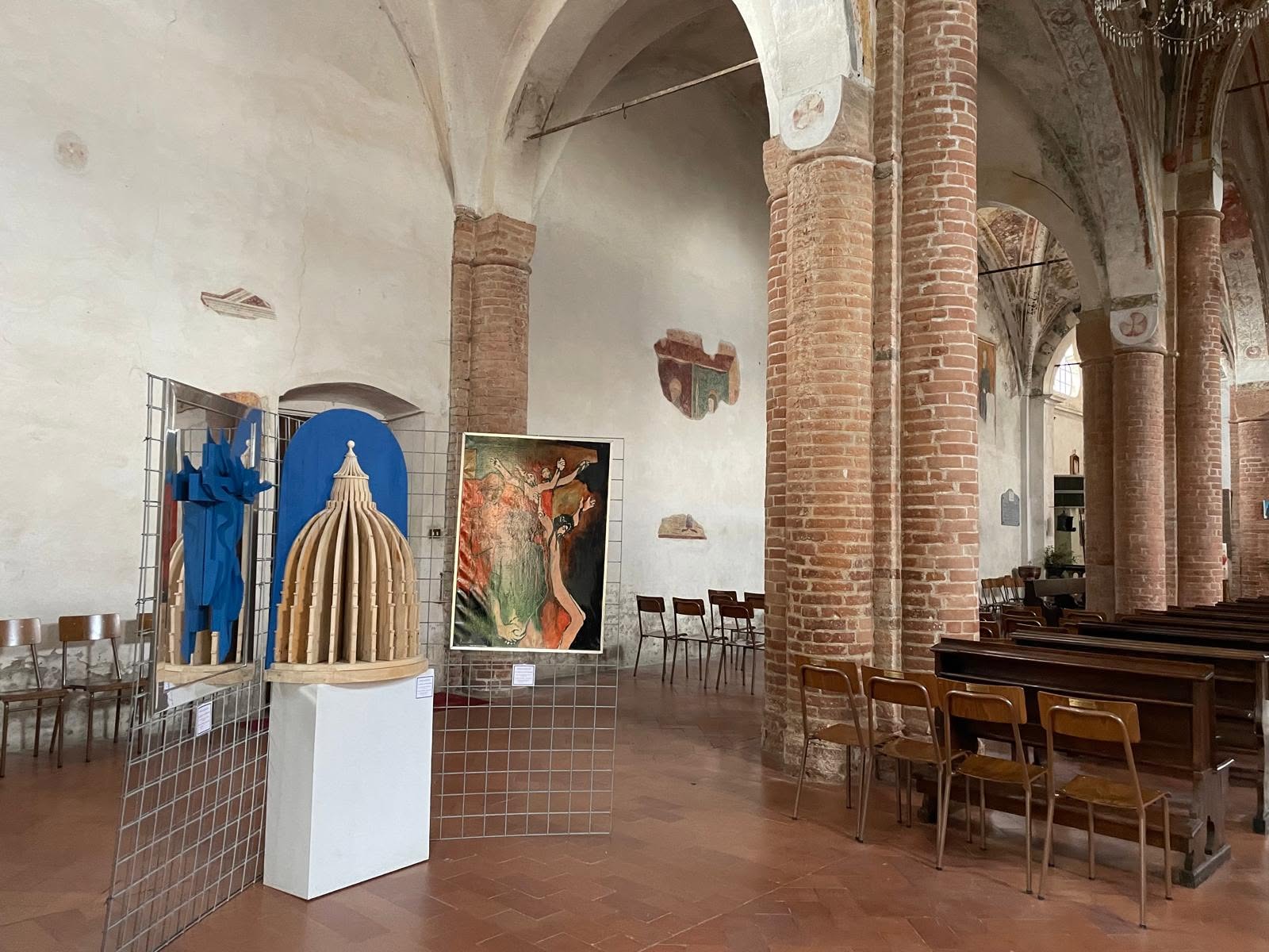 Navata di una chiesa con opere esposte tra le colonne in mattoni
